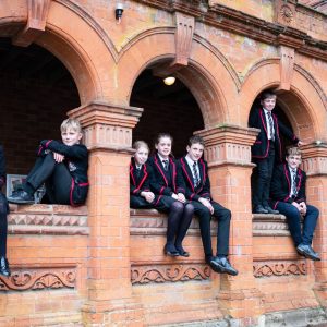 Lucton School children sitting in arches of red brick building